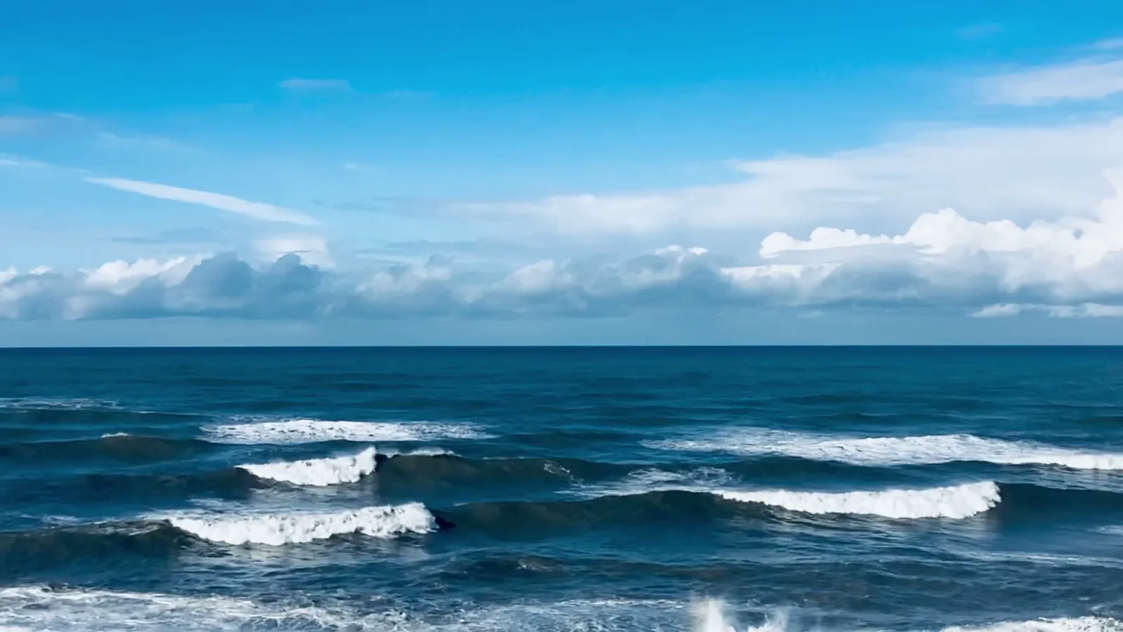 Ondas vistas da praia sob a linha do horizonte